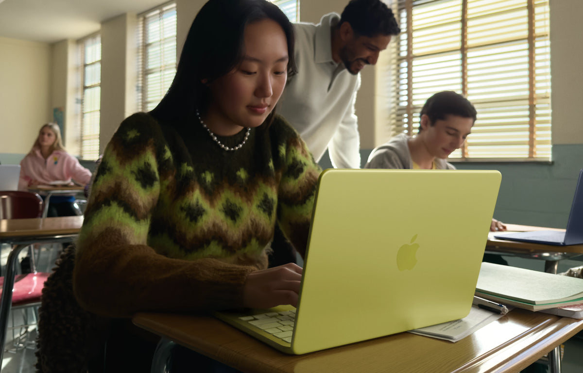 Person using a citrus color macbook neo in a classroom setting with other students and a teacher. in Mauritius shop at iStore